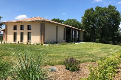 Un couple dans une voiture ancienne quitte un bâtiment entouré de verdure par une journée ensoleillée.