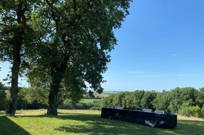 Un couple dans une voiture ancienne quitte un bâtiment entouré de verdure par une journée ensoleillée.