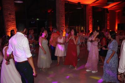Un couple dans une voiture ancienne quitte un bâtiment entouré de verdure par une journée ensoleillée.