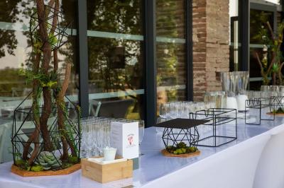 Un couple dans une voiture ancienne quitte un bâtiment entouré de verdure par une journée ensoleillée.