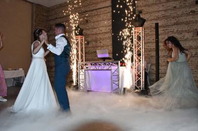 Un couple dans une voiture ancienne quitte un bâtiment entouré de verdure par une journée ensoleillée.