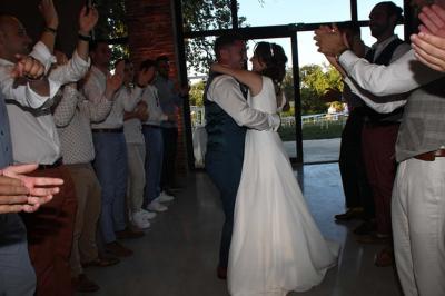 Un couple dans une voiture ancienne quitte un bâtiment entouré de verdure par une journée ensoleillée.