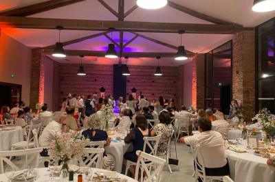 Un couple dans une voiture ancienne quitte un bâtiment entouré de verdure par une journée ensoleillée.