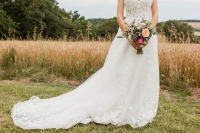 Un couple dans une voiture ancienne quitte un bâtiment entouré de verdure par une journée ensoleillée.