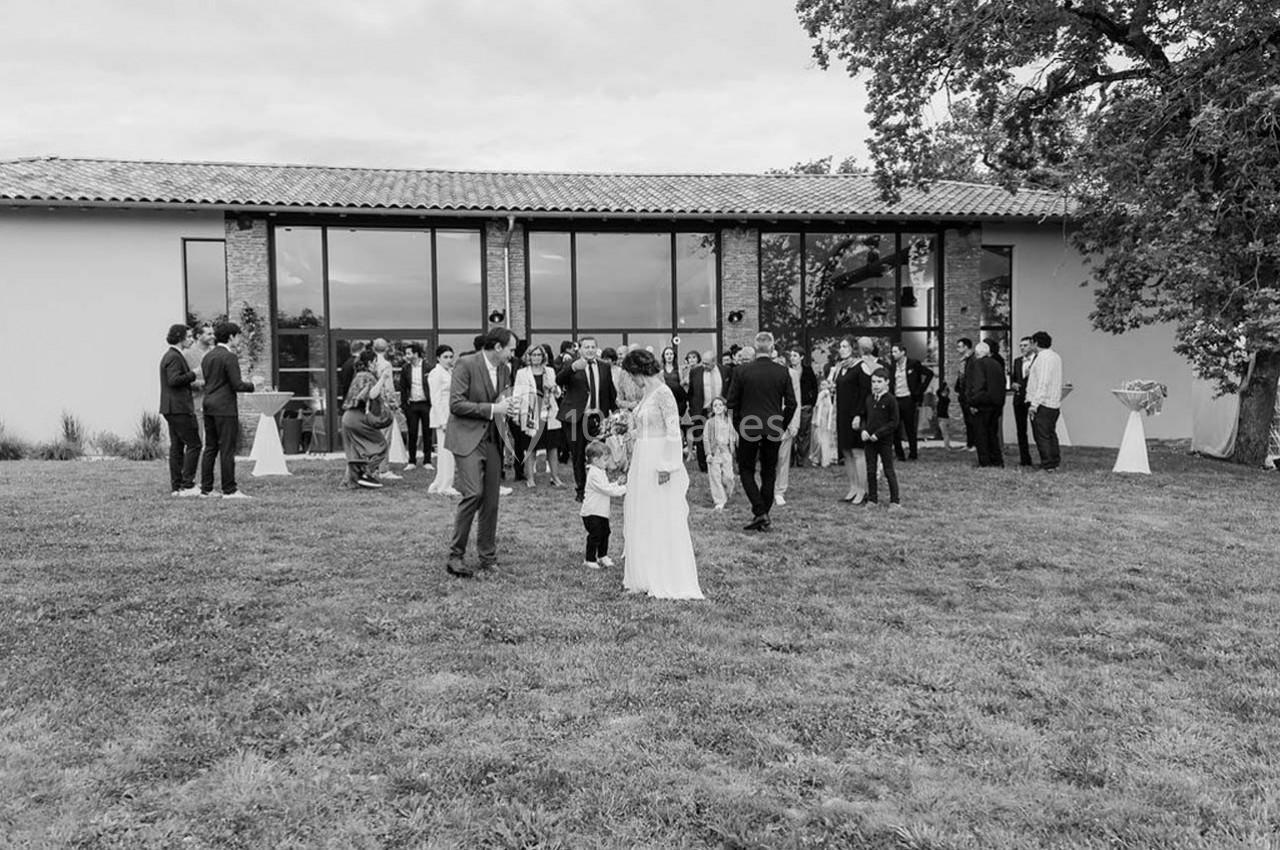 Groupe de personnes rassemblées sur une pelouse devant un bâtiment moderne avec de grandes baies vitrées.