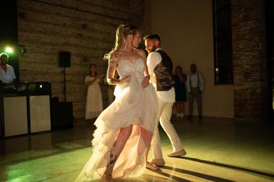 Un couple dans une voiture ancienne quitte un bâtiment entouré de verdure par une journée ensoleillée.