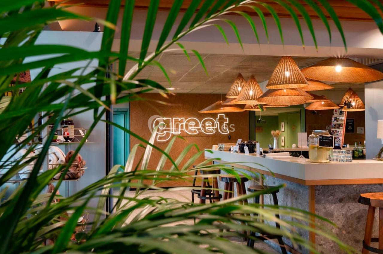 Espace d'accueil lumineux avec comptoir moderne, décor en bois et plantes, éclairé par des suspensions en osier.