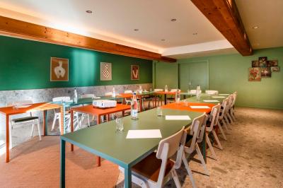 Chambre moderne avec deux lits, mur vert, télévision murale, bouilloire sur étagère et lumière douce.