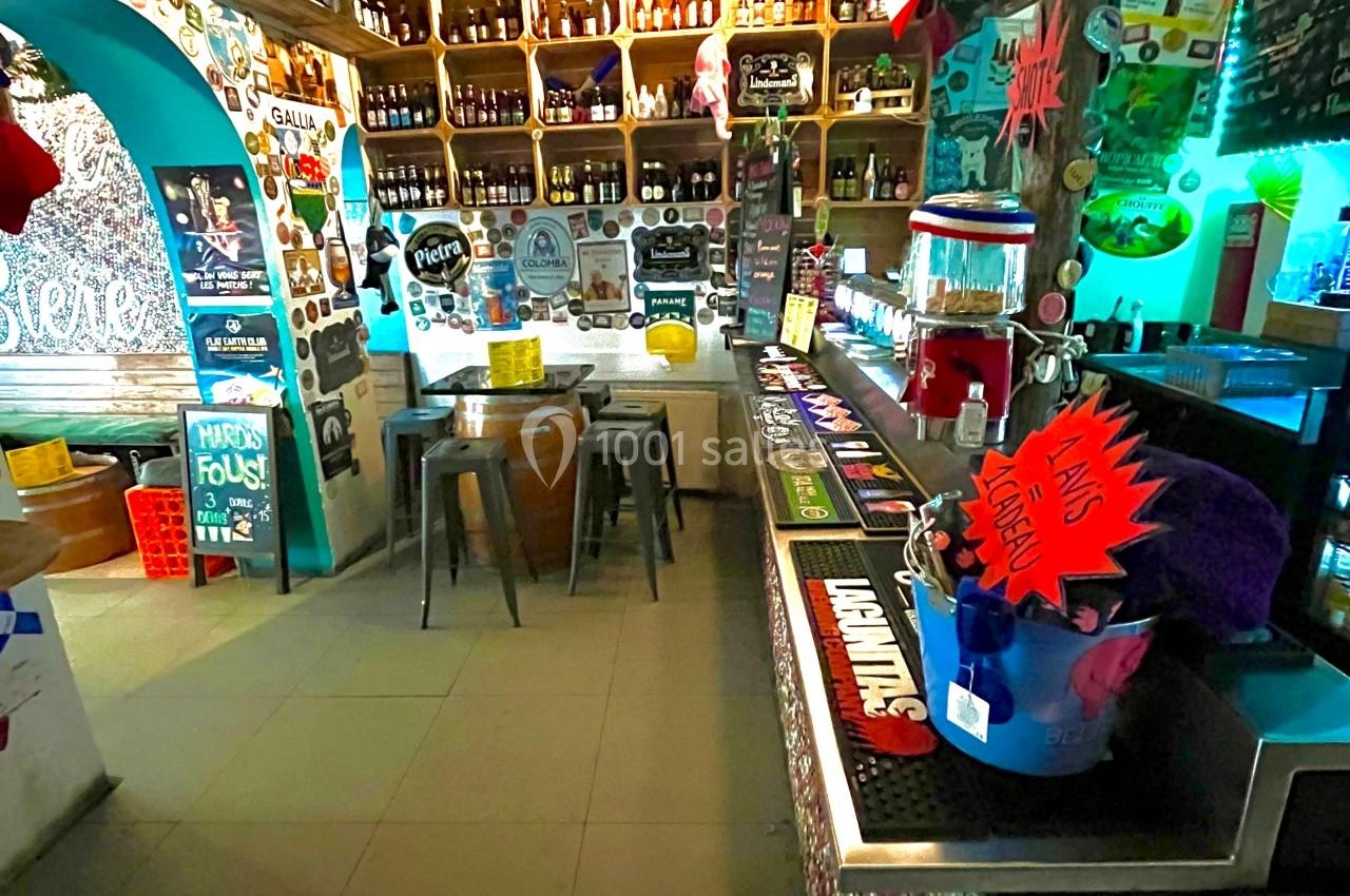 Intérieur d'un bar coloré avec étagères remplies de bouteilles, comptoir décoré et ambiance chaleureuse.