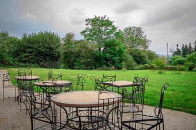 Chambre lumineuse avec un lit double, une grande fenêtre donnant sur un paysage verdoyant, et un fauteuil ancien.