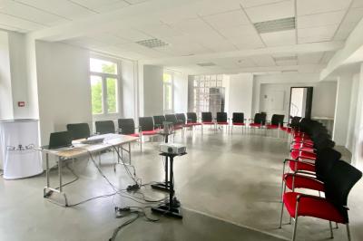 Chambre lumineuse avec un lit double, une grande fenêtre donnant sur un paysage verdoyant, et un fauteuil ancien.
