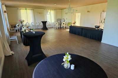 Chambre lumineuse avec un lit double, une grande fenêtre donnant sur un paysage verdoyant, et un fauteuil ancien.