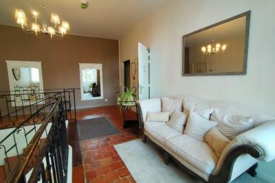 Chambre lumineuse avec lit double, banc capitonné, bureau en bois, lampe et miroir sur un parquet en bois clair.