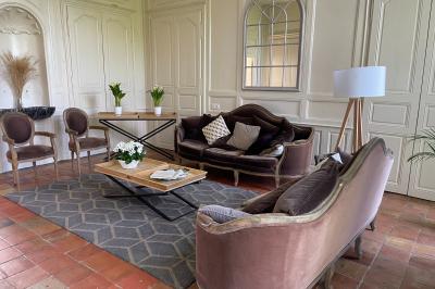Chambre lumineuse avec lit double, banc capitonné, bureau en bois, lampe et miroir sur un parquet en bois clair.
