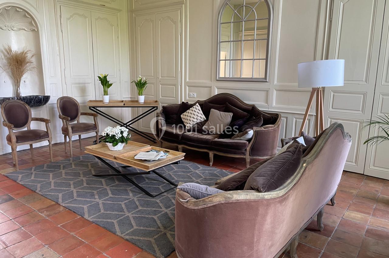 Salon élégant avec canapés en velours, table basse en bois, plantes décoratives et miroir mural dans un intérieur lumineux.