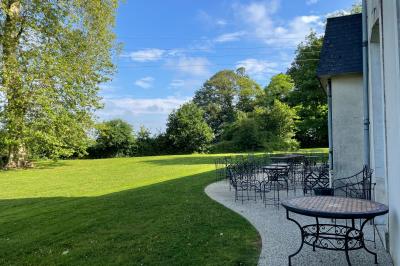 Chambre lumineuse avec lit double, banc capitonné, bureau en bois, lampe et miroir sur un parquet en bois clair.
