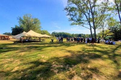 Tente tipi blanche installée sur une pelouse avec une table de pique-nique à proximité, entourée de verdure.