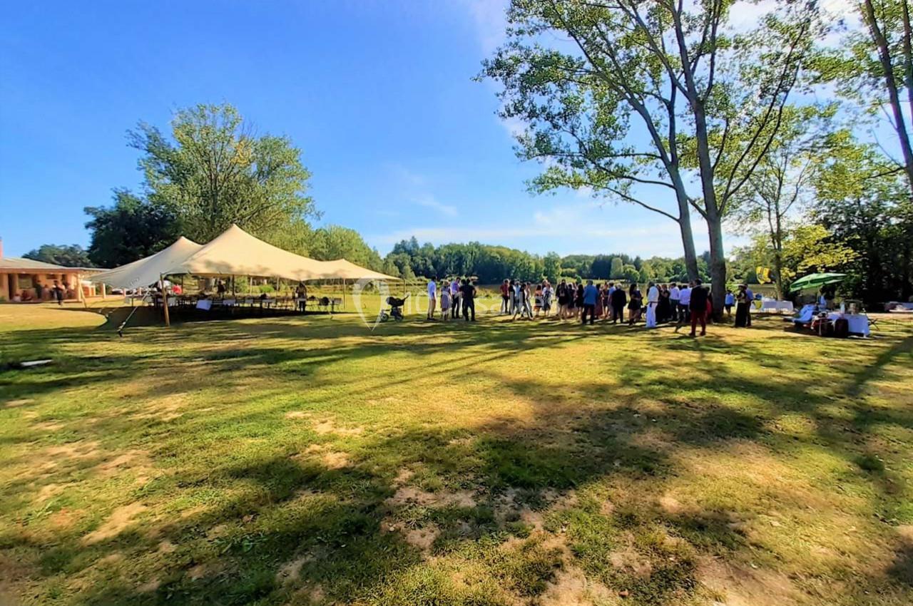 Groupe de personnes rassemblées dans un parc verdoyant sous des tentes par une journée ensoleillée.