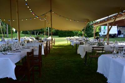 Tente tipi blanche installée sur une pelouse avec une table de pique-nique à proximité, entourée de verdure.