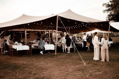 Tente tipi blanche installée sur une pelouse avec une table de pique-nique à proximité, entourée de verdure.