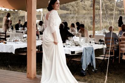 Tente tipi blanche installée sur une pelouse avec une table de pique-nique à proximité, entourée de verdure.