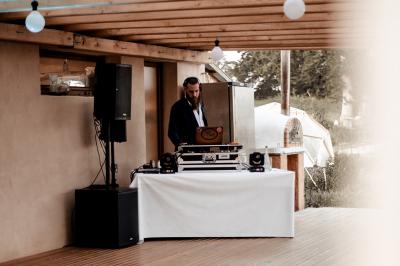 Tente tipi blanche installée sur une pelouse avec une table de pique-nique à proximité, entourée de verdure.