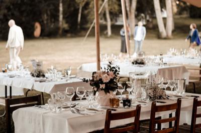 Tente tipi blanche installée sur une pelouse avec une table de pique-nique à proximité, entourée de verdure.