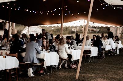 Tente tipi blanche installée sur une pelouse avec une table de pique-nique à proximité, entourée de verdure.