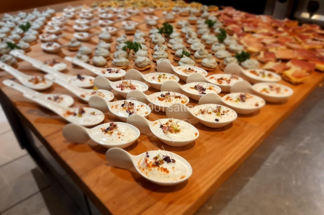 Assortiment de bouchées apéritives disposées sur une table en bois, incluant des cuillères garnies et des toasts variés.