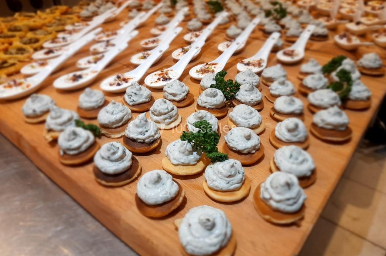 Plateau de bouchées apéritives variées, incluant des cuillères et des canapés garnis de crème et d'herbes fraîches.