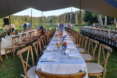 Tente tipi blanche installée sur une pelouse avec une table de pique-nique à proximité, entourée de verdure.