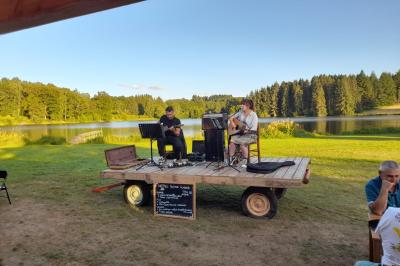 Tente tipi blanche installée sur une pelouse avec une table de pique-nique à proximité, entourée de verdure.