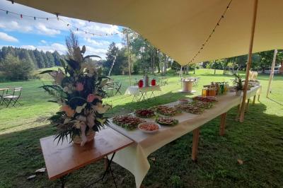 Tente tipi blanche installée sur une pelouse avec une table de pique-nique à proximité, entourée de verdure.