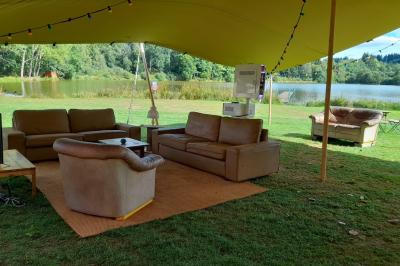 Tente tipi blanche installée sur une pelouse avec une table de pique-nique à proximité, entourée de verdure.