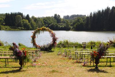 Tente tipi blanche installée sur une pelouse avec une table de pique-nique à proximité, entourée de verdure.