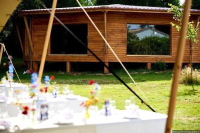 Tente tipi blanche installée sur une pelouse avec une table de pique-nique à proximité, entourée de verdure.