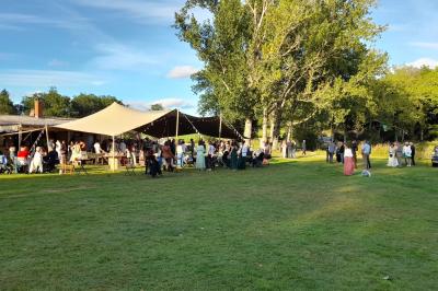 Tente tipi blanche installée sur une pelouse avec une table de pique-nique à proximité, entourée de verdure.