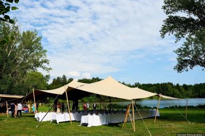 Tente tipi blanche installée sur une pelouse avec une table de pique-nique à proximité, entourée de verdure.