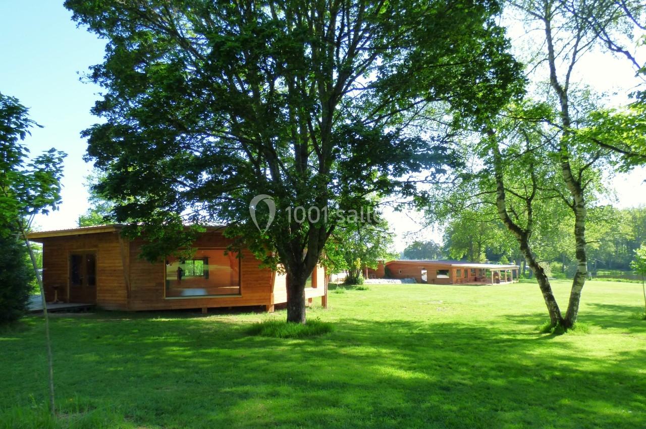 Chalets en bois entourés d'arbres et d'une pelouse verte sous un ciel dégagé.