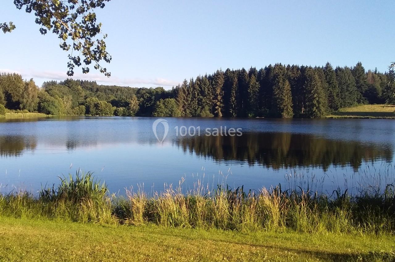Vue d'un lac entouré de forêt et de végétation sous un ciel dégagé.