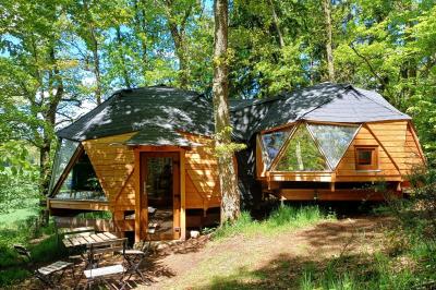 Tente tipi blanche installée sur une pelouse avec une table de pique-nique à proximité, entourée de verdure.
