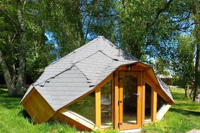 Tente tipi blanche installée sur une pelouse avec une table de pique-nique à proximité, entourée de verdure.
