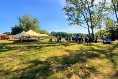 Cabane en bois avec toit en tuiles grises, grandes fenêtres et porte vitrée, située dans un espace arboré.