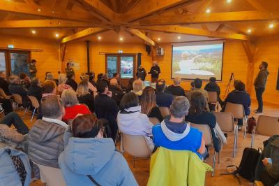 Cabane en bois avec toit en tuiles grises, grandes fenêtres et porte vitrée, située dans un espace arboré.