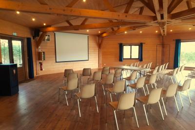 Cabane en bois avec toit en tuiles grises, grandes fenêtres et porte vitrée, située dans un espace arboré.