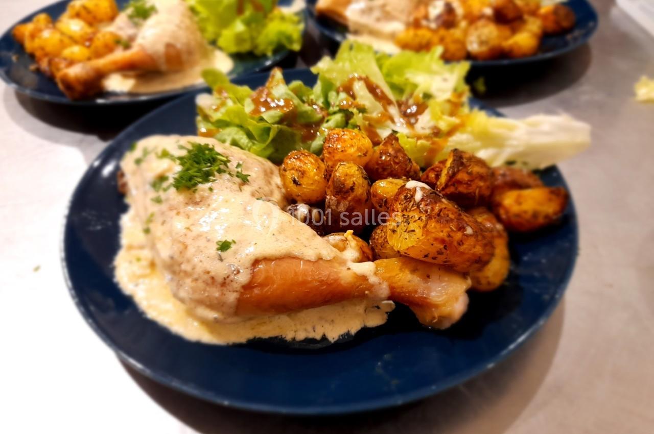 Assiette contenant un morceau de poulet en sauce, des pommes de terre rôties et une salade verte.