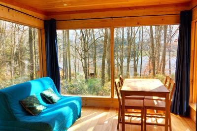 Cabane en bois avec toit en tuiles grises, grandes fenêtres et porte vitrée, située dans un espace arboré.