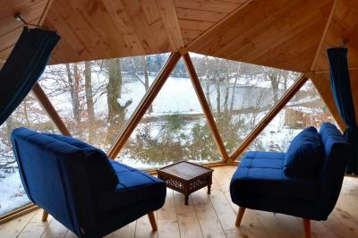 Cabane en bois avec toit en tuiles grises, grandes fenêtres et porte vitrée, située dans un espace arboré.