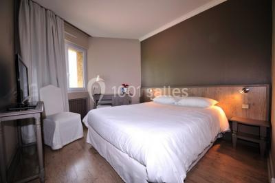 Salle de bain moderne avec douche arrondie, lavabo avec miroir éclairé et carrelage sombre.