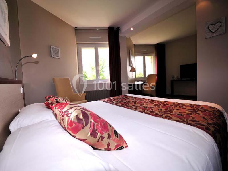 Chambre lumineuse avec un lit double, une décoration chaleureuse, un bureau, une chaise et une fenêtre donnant sur l…